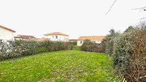 une cour avec de l'herbe verte et une maison en arrière-plan dans l'établissement Maison cosy, bien équipée, 15 min Futuroscope, CHU, à Poitiers