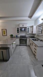 a large kitchen with white cabinets and appliances at Elegant Oasis by the Sea in Saint Annʼs Bay