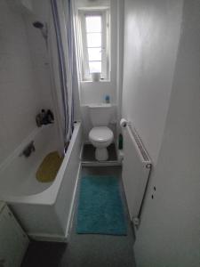a bathroom with a toilet and a tub and a window at Super Streatham Room in London