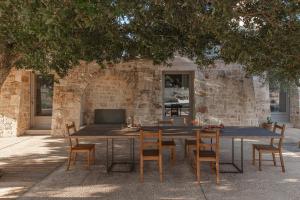 a wooden table and chairs in front of a brick wall at Trulli Mest'Andrea alle lame in Noci