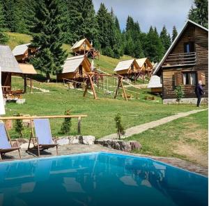 a large pool in front of a log cabin at Eko Katun Bungalows Jelovica in Berane