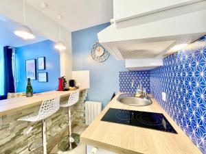 - une cuisine avec un évier et un mur bleu dans l'établissement A L'ABORDAGE APPART - Lorient centre - Au calme, à Lorient