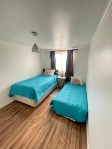 Casa en Puerto Montt في بويرتو مونت: سريرين في غرفة صغيرة مع أرضيات خشبية