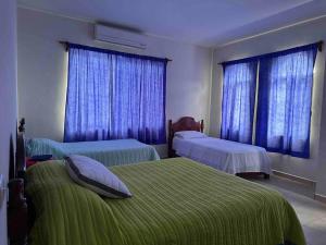 1 dormitorio con 2 camas y cortinas azules en Casa Coy, en Ciudad Valles