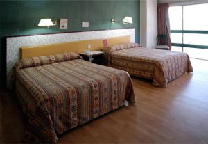 2 camas en una habitación de hotel con paredes verdes en Hotel Montreal, en León