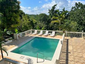 a swimming pool with chairs and a white fence at Retreat Guest House in Falmouth