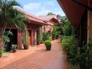 a red house with potted plants on a brick walkway at Magadan Residence in Pattaya South