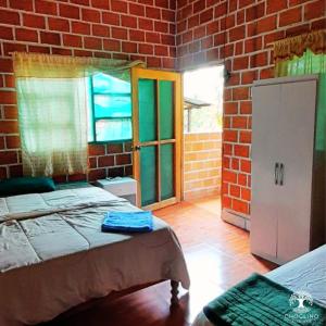 1 dormitorio con cama y pared de ladrillo en CHOCLINO ECOLODGE -Bungalows en Tarapoto