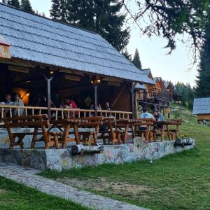 a bar with wooden benches in front of a building at Eko Katun Bungalows Jelovica in Berane