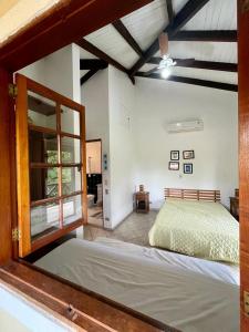 1 dormitorio con cama y ventana grande en Paúba Beach House, en São Sebastião