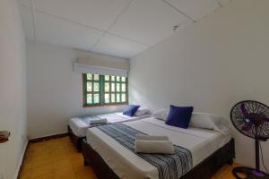 a bedroom with two beds and a fan at CASA DE CAMPO CASTILLETE dentro del PARQUE TAYRONA in Santa Marta