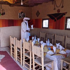 a man standing next to a table in a restaurant at Camp Familia Erg Chebbi in Merzouga