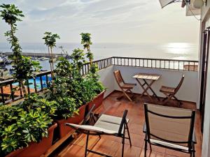 Un balcón con sillas, una mesa y el océano en Piso en Candelaria con terraza, vistas al mar, aire acondicionado y garaje, en Candelaria