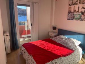 1 dormitorio con 1 cama con manta roja y ventana en Valberg 3 pièces au pied des pistes en Péone