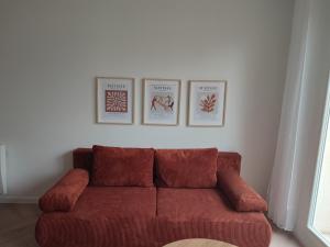 a red couch in a room with three pictures on the wall at Appartement d'architecte avec vue sur jardin in La Courneuve