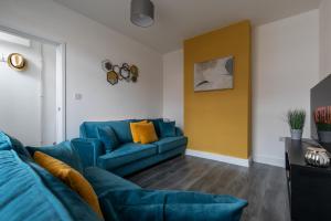 a living room with a blue couch and a yellow wall at Sunbeam cottage contractor Parking WiFi Garden in Colchester