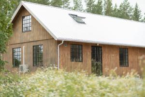 a wooden barn with a white roof and windows at A Place to Call Home in Skellefteå