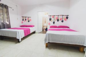 2 camas en una habitación blanca con sábanas rosas en Zayali Bacalar - Guest House, en Bacalar