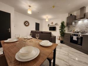 eine Küche und ein Wohnzimmer mit einem Tisch und Weingläsern in der Unterkunft ApartHotel Flat 1 - 10 min to centre by Property Promise in Cardiff