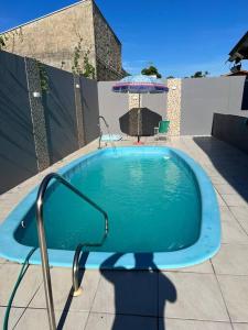 a swimming pool with an umbrella and a chair at Casa aconchegante ótima para rlx in Barra Velha