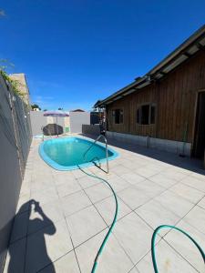 a swimming pool with a green hose on a patio at Casa aconchegante ótima para rlx in Barra Velha