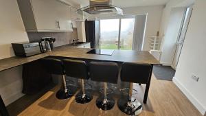 a kitchen with a counter with black bar stools at Cosy Corner Suite in Bradford