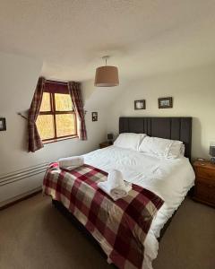 a bedroom with a bed with a blanket and a window at Runaway Cottage, Whitby in Whitby