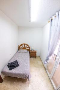 um pequeno quarto com uma cama e uma janela em Elvira 81 em Granada