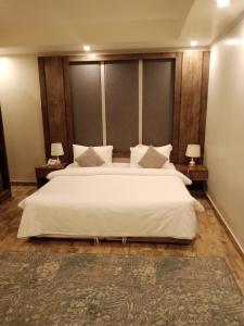 吉達的住宿－فندق العنقود - قريش，卧室配有一张白色大床和两盏灯。