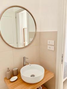 La salle de bains est pourvue d'un lavabo blanc et d'un miroir. dans l'établissement Camere Assúd, à Leuca