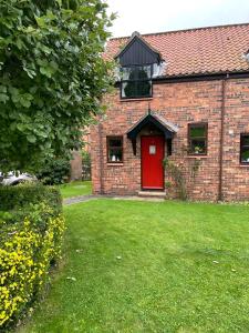 a red brick house with a red door and a yard at Runaway Cottage, Whitby in Whitby