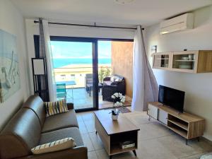 een woonkamer met een bank en een televisie bij Appartement vue mer panoramique près de Porticcio in Pietrosella