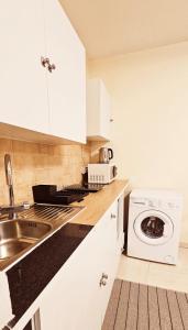 uma cozinha branca com um lavatório e uma máquina de lavar roupa em studio em Agia Napa