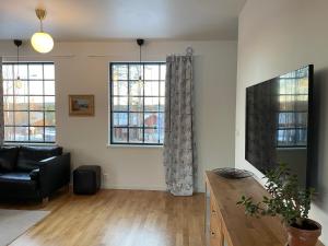 a living room with a black couch and two windows at A Place to Call Home in Skellefteå