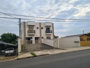 a white house with a fence in front of it at Ap 03 edificio Sao Paulo I in Ponta Grossa