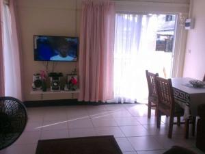 sala de estar con mesa y TV en la pared en Villa Nickerie/ Suriname, en Nieuw Nickerie
