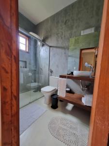 a bathroom with a shower and a toilet and a sink at Pousada TAUANE in Caraíva