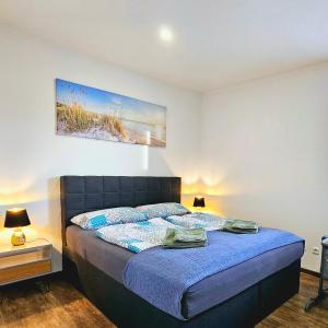 1 dormitorio con 1 cama con sábanas azules y una pintura en la pared en Exklusive Ferienwohnung in Lingen Holthausen 2Zim, 2Badez,Küche,Balkon,Waschmaschine, en Lingen