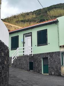 uma casa verde e branca com uma varanda branca em Mar Rosa - Terraço Vista Praia em Horta