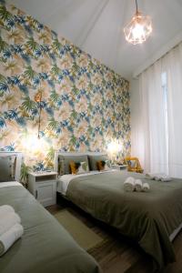 una camera con due letti e una parete ricoperta di carta da parati di Casa Cosmedin a Napoli