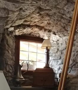 a window in a stone wall with a lamp on a table at La Thuillettaz B&B in Saint-Rhémy-en-bosses