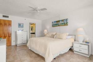 a bedroom with a white bed and a ceiling fan at Beachfront Condo with Pool and Hot Tub Reflections On The Gulf 504 in Clearwater Beach +24 photos