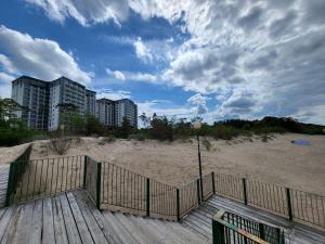 eine hölzerne Promenade, die zu einem Strand mit hohen Gebäuden führt in der Unterkunft APT. 539 in Dziwnówek