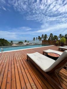 a wooden deck with a couch and a pool at Beira mar rota dos milagres - Porto de pedras AL in Pôrto de Pedras