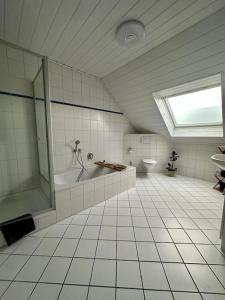 ein Badezimmer mit einer Dusche, einer Badewanne und einem WC in der Unterkunft Stilvoll eingerichtetes Ferienhaus in ruhiger Lage in Bremerhaven