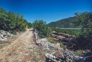 un chemin de terre avec une clôture sur le côté d'une montagne dans l'établissement Robinson Haus Ivan, à Makarska