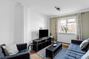 a living room with a couch and a tv at Cosy 2 Bedroom Flat in East Ham, Close to Excel in London