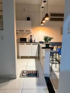 cocina con armarios blancos, mesa y sillas en Apartamento no coração de BH!, en Belo Horizonte