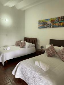 a bedroom with two beds and a painting on the wall at Hostal greenlandomesa in Piedecuesta