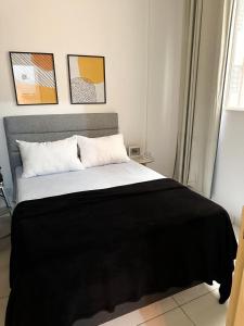 a bedroom with a large bed with a black blanket at Apartamento no coração de BH! in Belo Horizonte